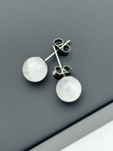 Øreringe studs med hvide bjergkrystalkugler på hvid baggrund