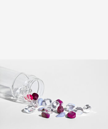 Krystalsæt som ligger i en vandflaske på en hvid baggrund. Klar kvarts