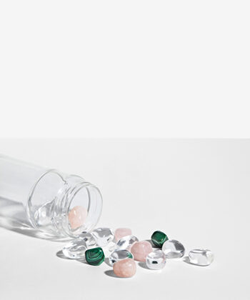 Krystalsæt som ligger i en vandflaske på en hvid baggrund. Klar kvarts