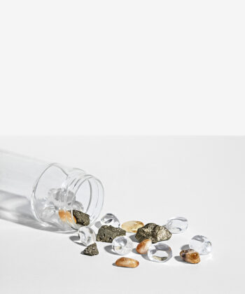 Krystalsæt som ligger i en vandflaske på en hvid baggrund. Gylden pyrit