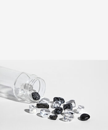 Krystalsæt som ligger i en vandflaske på en hvid baggrund. Klar kvarts