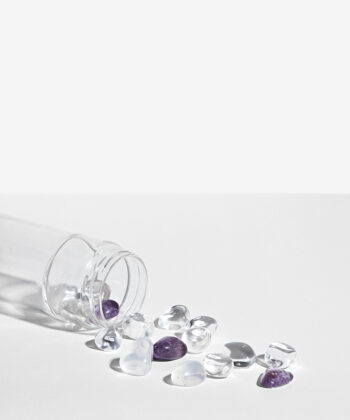 Krystalsæt som ligger i en vandflaske på en hvid baggrund. Klar kvarts og Lilla Ametyst