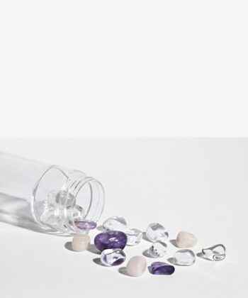 Krystalsæt som ligger i en vandflaske på en hvid baggrund. Klar kvarts