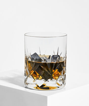 Fine sorte Shungit kuber brugt som isterninger i et glas whisky. Billedet er taget på hvid baggrund