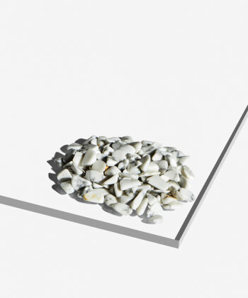 En bunke hvide polerede Howlit Ministen med grå aflejringer og gyldne detaljer på hvid baggrund