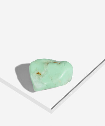 Turkisgrøn poleret Chrysopras sten med rustfarvede detaljer på hvid baggrund