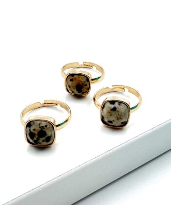 guld farvet ring med sort plettet sten på hvid baggrund