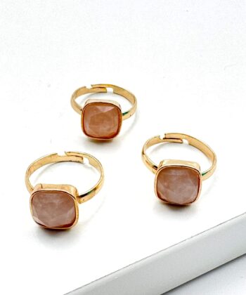 guld farvet ring med lyserød sten på hvid baggrund