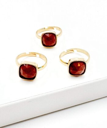 rød orange glimmer sten i guldfarvet ring på hvid baggrund