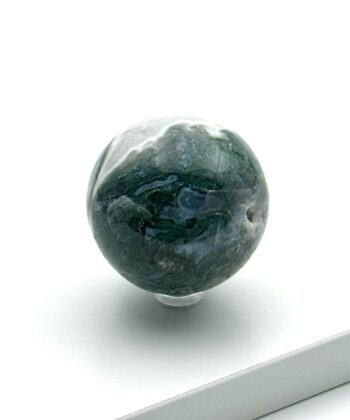 Mørkegrøn og hvid krystalkugle med lyseblå detaljer på hvid baggrund