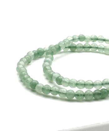 To lysegrønne armbånd med halvædelsten på hvid baggrund