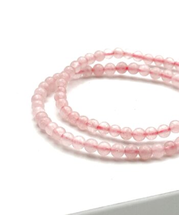 To lyserøde armbånd med halvædelsten på hvid baggrund