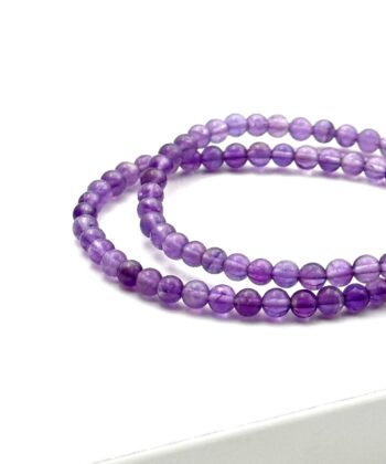 To lilla armbånd med halvædelsten på hvid baggrund