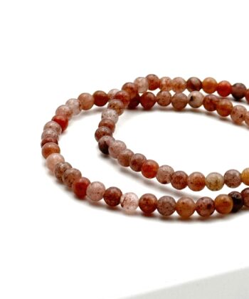 To rødbrune armbånd med halvædelsten på hvid baggrund