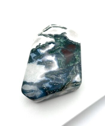 Dyb grøn og hvid poleret krystal med lyseblå detaljer på hvid baggrund