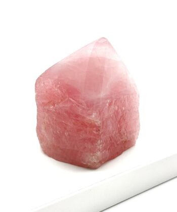 Lyserød rå krystal med stump poleret spids på hvid baggrund