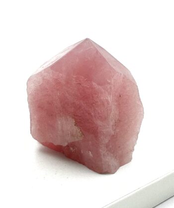 Lyserød rå krystal med poleret spids på hvid baggrund