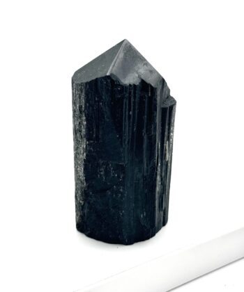 Sort rå krystal med poleret spids på hvid baggrund