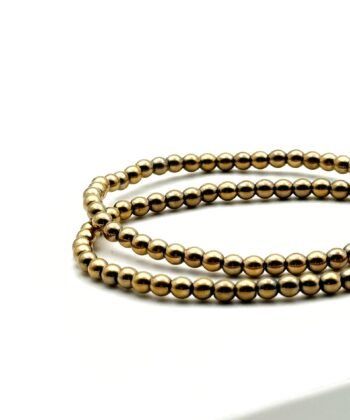 To elastik armbånd med runde guldfarvede stenperler