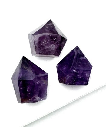 Tre lilla ametyst mangekantede figurer på hvid baggrund