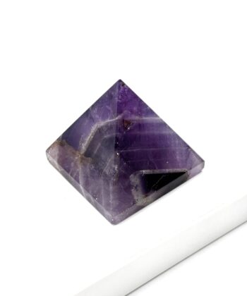 Lilla ametyst pyramide fotograferet på hvid baggrund