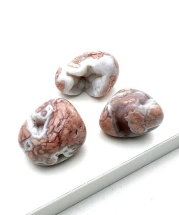 Tre polerede halvædelsten i rosa og hvid med rå detaljer på hvid baggrund