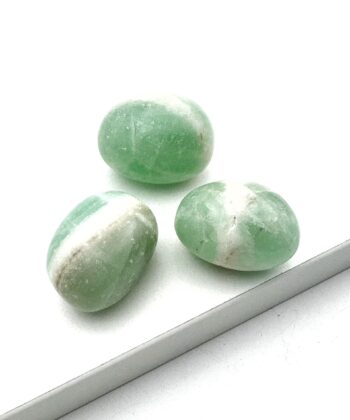 Tre æblegrønne polerede halvædelsten med hvide detaljer på hvid baggrund