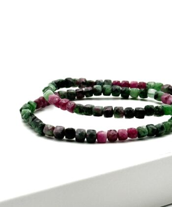 Armbånd med sorte, grønne og pink sten på hvid baggrund