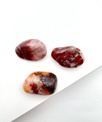 Mørkrøde og let orange afrundede krystaller på hvid baggrund