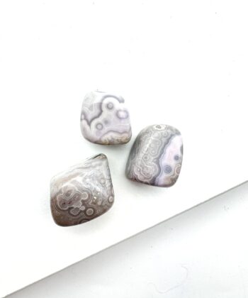 Lysegrå og mildt violette afrundede krystaller på hvid baggrund