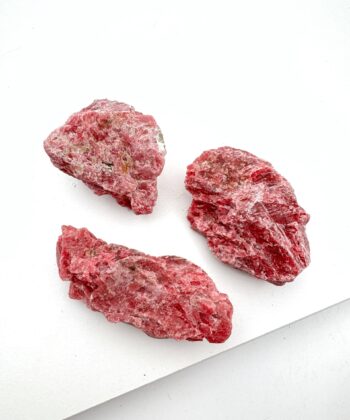 Mørk lyserøde rå krystaller på hvid baggrund