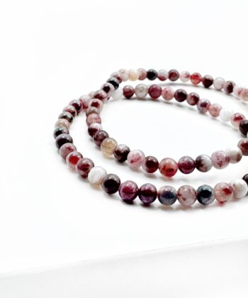 Armbånd med pinke, sorte og hvide kugler på hvid baggrund