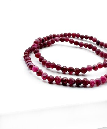 Facet armbånd med bordeauxfarvede runde kugler på hvid baggrund