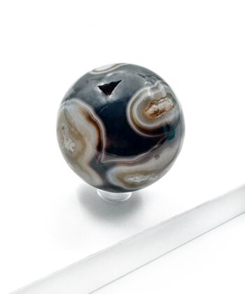 Sort agat kugle med hvide brune blonder rund poleret på hvid baggrund