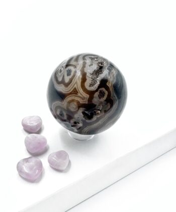 Sort agat kugle med hvide brune blonder rund poleret på hvid baggrund