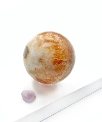 Varm gullig gylden orange calcit kugle glat poleret rund på hvid baggrund
