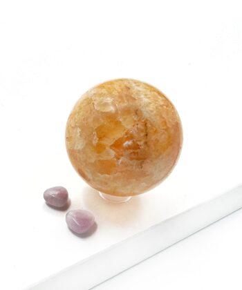 Varm gullig gylden orange calcit kugle glat poleret rund på hvid baggrund
