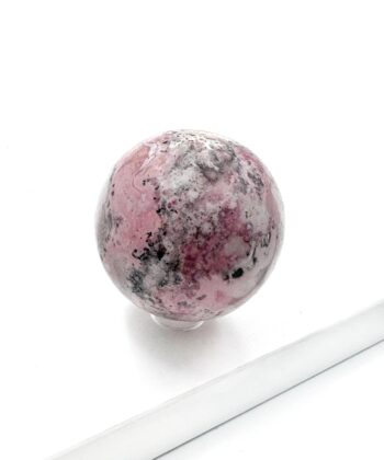 Lyserød hvid grå sort marmoreret krystalstens kugle glat poleret på hvid baggrund