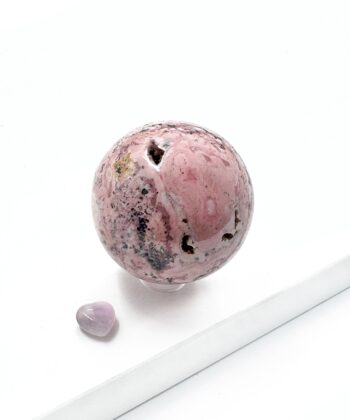 Lyserød hvid grå sort marmoreret krystalstens kugle rund poleret på hvid baggrund