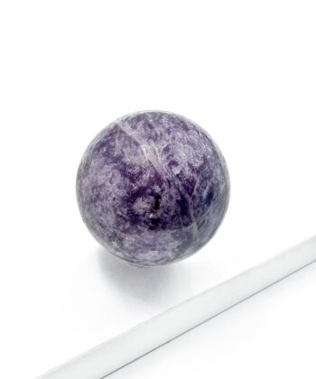 Mørk og lyse lilla lepidolit krystal kugle rund glat poleret på hvid baggrund