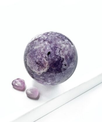 Mørk og lyse lilla lepidolit krystal kugle rund glat poleret på hvid baggrund