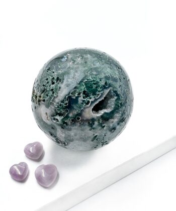 Mos agat kugle poleret med naturlige uddybninger og sugar druzy med grønlige hvide nuancer på hvid baggrund