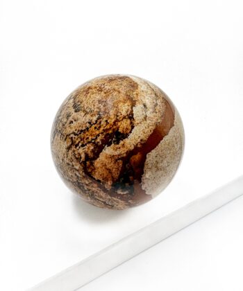 Sandfarvet brun mønstret krystal kugle glat poleret på hvid baggrund