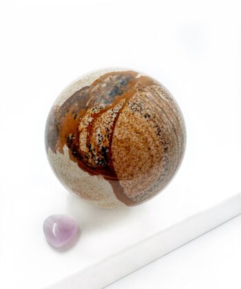 Sandfarvet brun mønstret krystal kugle glat poleret på hvid baggrund