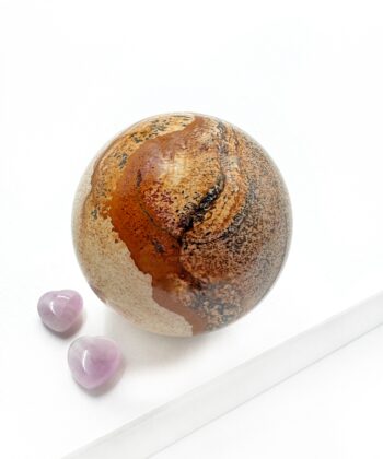 Sandfarvet brun mønstret krystal kugle glat poleret på hvid baggrund