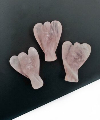 Tre lyserøde rosenkvarts engle figurer på sort plade på hvid baggrund