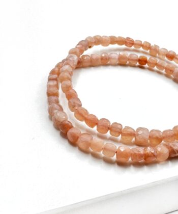 Armbånd med fersken farvet krystalsten facetslebet perler på hvid baggrund