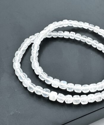 Armbånd med hvide klare krystalsten facetslebet perler på mørk baggrund