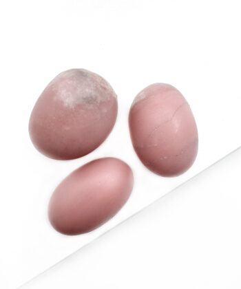 Runde polerede lyserøde krystal sten på hvid baggrund