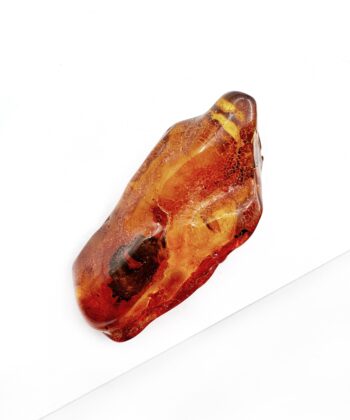 Cognac farvet freeform blødt poleret stykke rav på hvid baggrund
